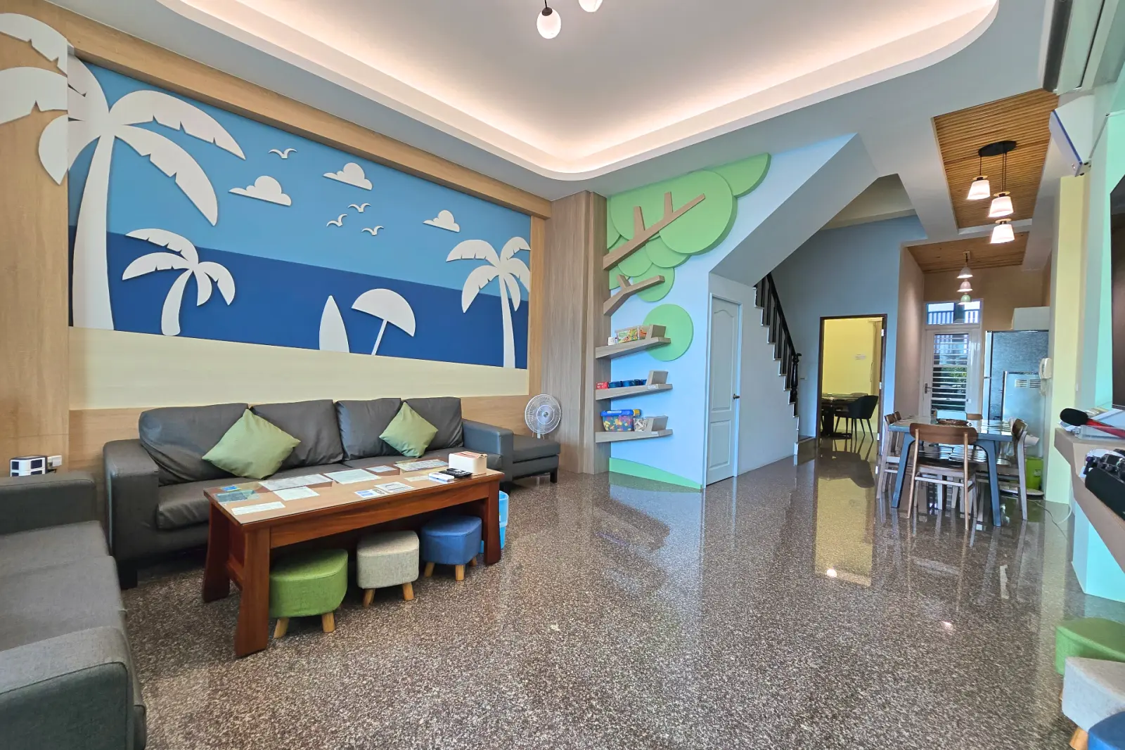 啾來玩包棟大廳，海灘主題壁畫、沙發與長桌餐區