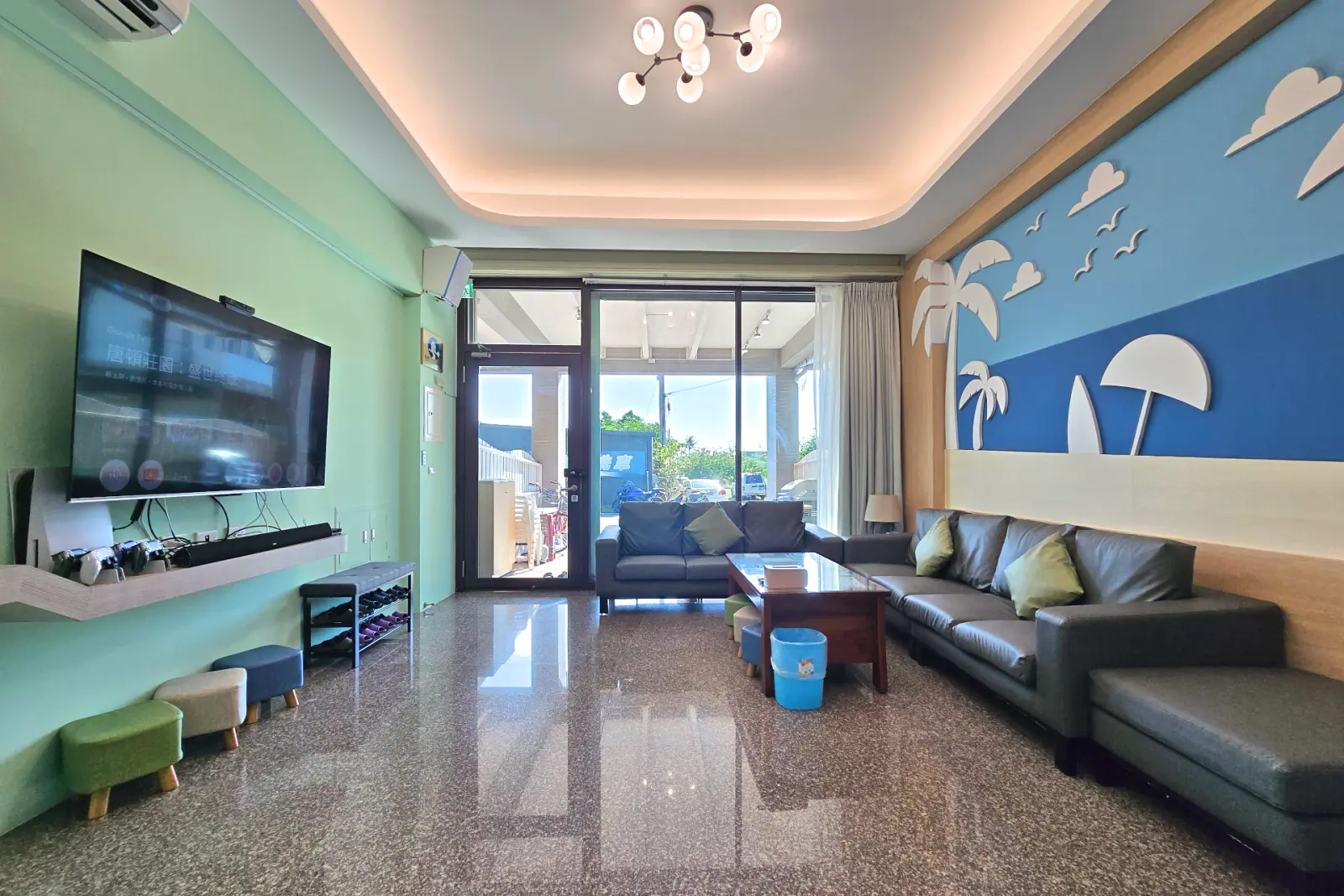 啾來玩包棟大廳，電視牆、L型沙發與通往前庭的落地門